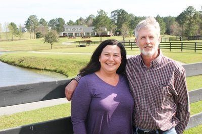 Mike and Donna Collins pose against a fence on their land