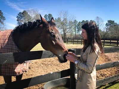 Mary Guynn touching a horse's nose over a fence
