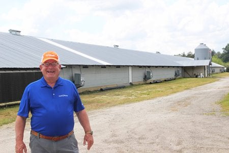 Coggins standing in front of a farm building