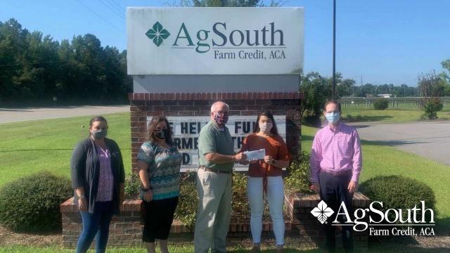 Masked people posing in front of AgSouth sign