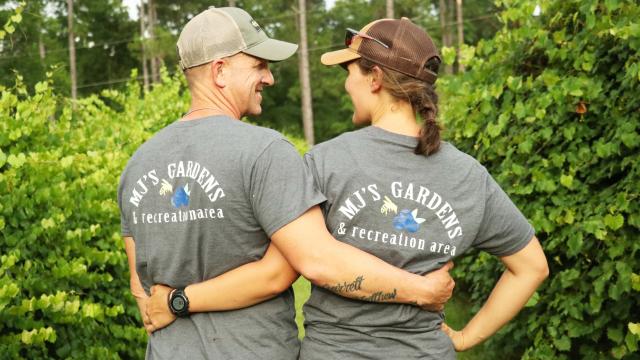 Couple wearing "MJ's Gardens and Recreation Area" t-shirts with an arm around each other's waists