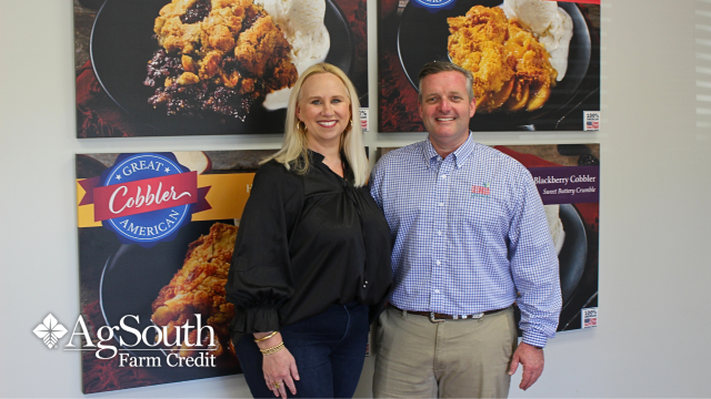 Members, Russ and Carra Goodman, standing in front of The Great American Cobbler Company posters.