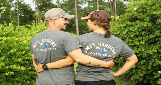 Couple wearing "MJ's Gardens and Recreation Area" t-shirts with an arm around each other's waists