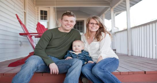 Man, woman and baby sitting on a front porch step